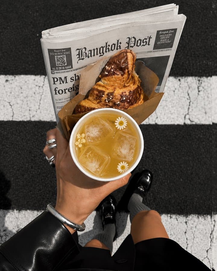 A TANICHA iced tea and a croissant on a Bangkok Post newspaper