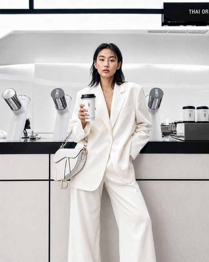 A model in a white suit holding a TANICHA cup at the counter
